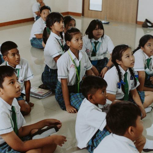 Children in School Uniforms Sitting on Floor in Classroom